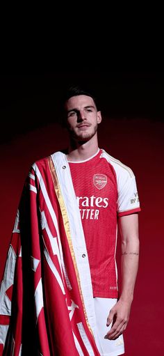 a man in a red and white shirt is holding a soccer jersey