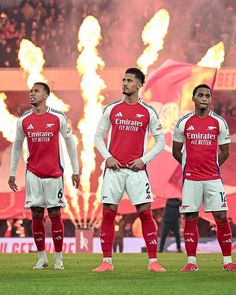 three soccer players are standing on the field with their hands in their pockets and looking up