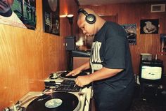 a man standing in front of a record player with headphones on and mixing music