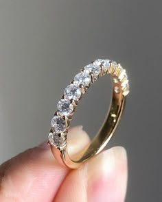 a close up of a person's hand holding a gold ring with five diamonds