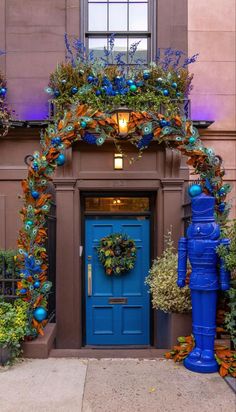 a blue door is decorated with greenery and lights in front of a tall building