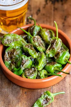 green peppers in a bowl next to a glass of beer