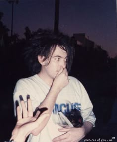 a young man holding his hands in front of his face with fake nails on it