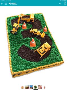 an image of a birthday cake with construction equipment on the top and green grass in the middle