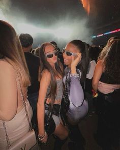 two girls in sunglasses are standing next to each other at a concert with fireworks behind them