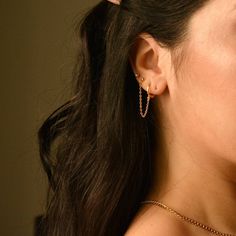 a close up of a person wearing some kind of earring with chains on it