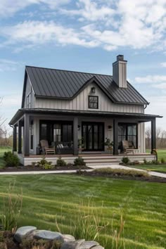 a house with a metal roof and two porches in the front yard, surrounded by grass