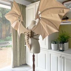 a mannequin dressed as a dragon with wings on display in front of a window