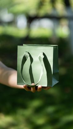 a person holding up a paper bag with the shadow of two people's legs on it