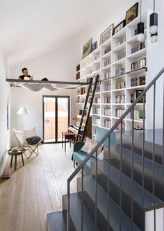 a person sitting on top of a stair case in front of a bookshelf