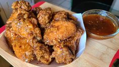 a bowl filled with fried chicken next to a jar of bbq sauce on a table