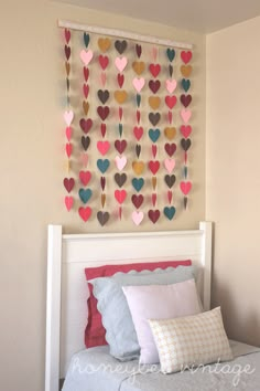 a white bed topped with pillows next to a wall hanging