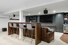 a living room filled with furniture and a flat screen tv mounted to the wall next to a bar