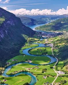 an aerial view of a golf course with mountains in the background and blue water running through it