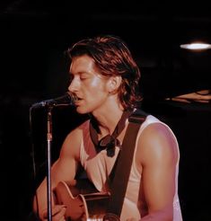 a young man playing an acoustic guitar in front of a microphone