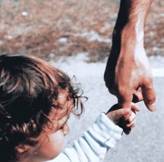 a young child holding the hand of an adult