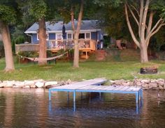 there is a dock in the water next to a house with a hammock on it