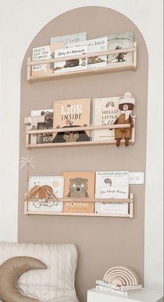 three wooden shelves with books on them in a living room next to a white chair