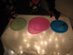 three frisbees sitting on top of a plastic box with lights around them