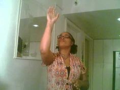 a woman standing in front of a mirror with her hand up to the ceiling and eyes closed