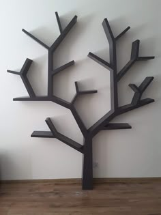 a metal tree sculpture sitting on top of a wooden floor next to a white wall