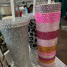 two vases with different colored beads on them sitting on a table next to each other