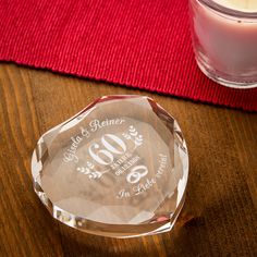 a personalized glass award sitting on a table next to a candle and red napkin