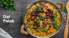 a large pot filled with food next to a wooden spoon and some parsley on the side