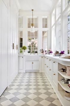 a white kitchen with checkered flooring and lots of window sill on the side