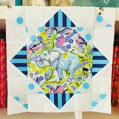 an elephant is depicted in the center of this quilted wallhanger, which has blue and white stripes on it