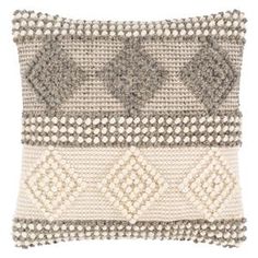 a gray and white pillow with an intricate design on the front, along with two different colors