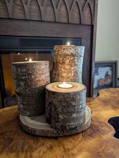 two candles sitting on top of logs in front of a fireplace