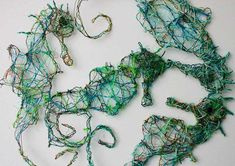 several pieces of string art on a white surface with green and blue yarn in the shape of animals