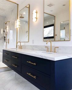 a bathroom with marble counter tops and two sinks in the middle, gold accents on the mirrors