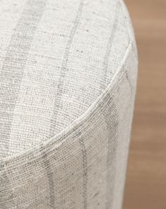 a close up view of the back end of a round ottoman cushion on a wooden floor