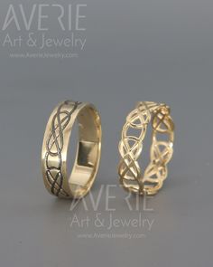 two gold wedding rings sitting on top of each other in front of a gray background