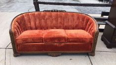 an orange couch sitting on top of a sidewalk