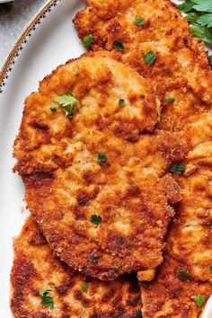 three fried patties on a plate with parsley sprinkled around the edges