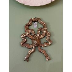 a metal object hanging on the wall next to a pink plate with a tag in it