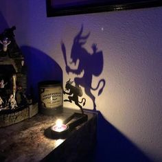 a shadow of a dragon on a wall next to a candle