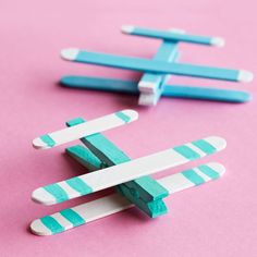 two popsicle sticks sitting next to each other on a pink surface with blue and white strips