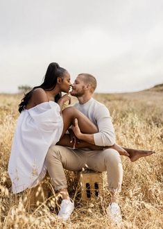 a man and woman are sitting on a bench in the middle of a wheat field