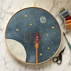 an embroidery project with scissors and thread on the table next to some other crafting supplies