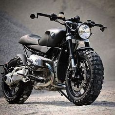 a black motorcycle parked on top of a cement floor next to a wall in front of a building