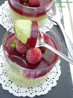 two dessert dishes with raspberry sauce and ice cream on the top one has a spoon in it