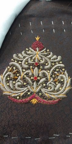 an embroidered christmas tree is shown on the back of a black jacket with red and gold details