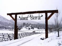 a sign that reads horse castle in front of snow covered hills and fenced roads