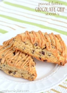 two chocolate chip cookies with peanut butter drizzled on top are sitting on a white plate