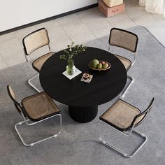 a black table with four chairs around it and a bowl of fruit on the table