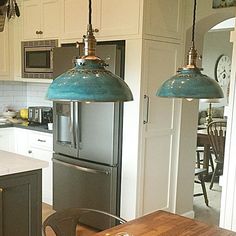 a kitchen with two pendant lights hanging over the stove top oven and refrigerator freezer